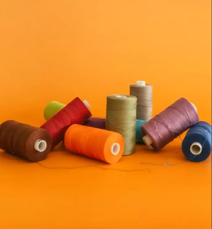 Bobines de fil colorées disposées sur un fond orange.