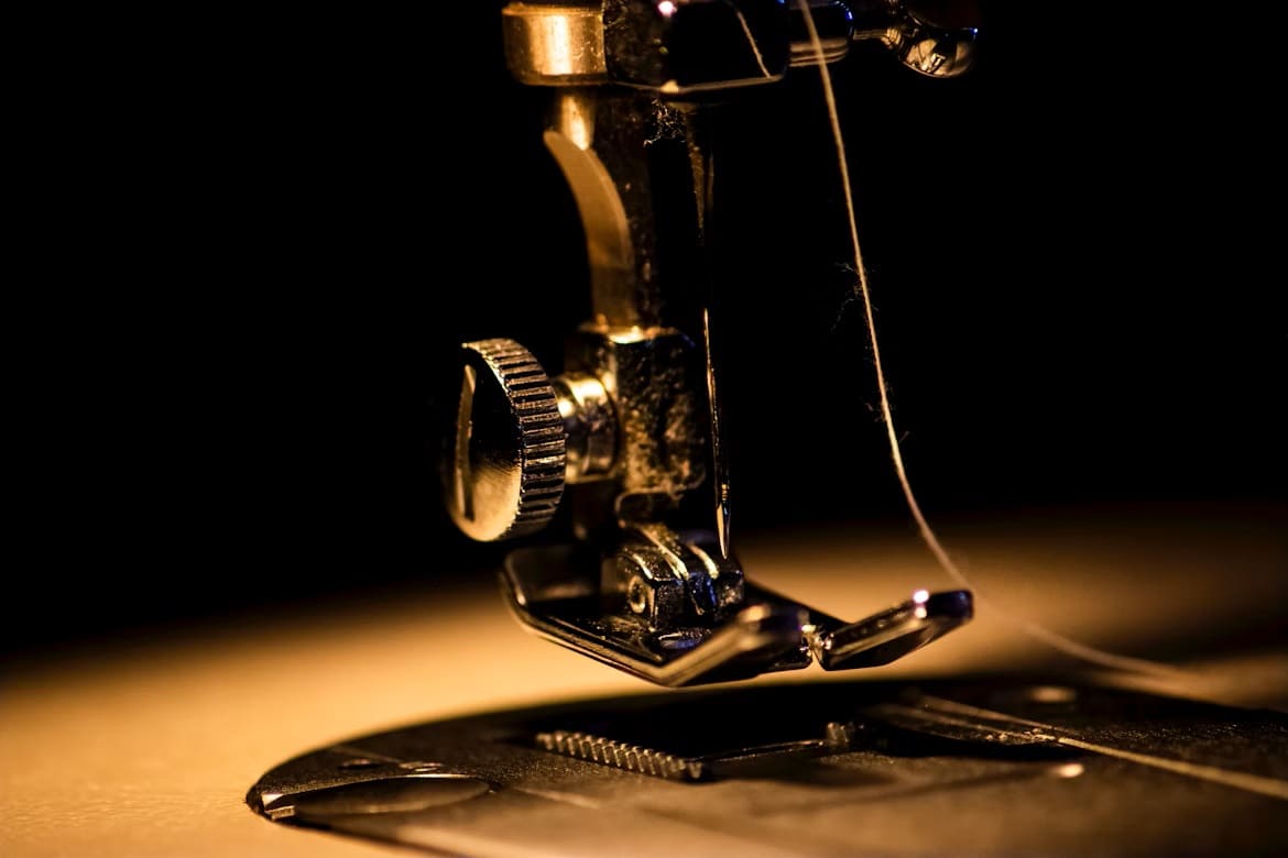 Gros plan du pied presseur et de l’aiguille d’une machine à coudre.