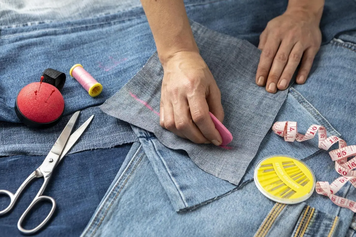 Retouche et upcycling d’un jean avec outils de couture.